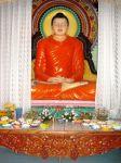 Buddhafigur mit den vielen Blumen im Vordergrund